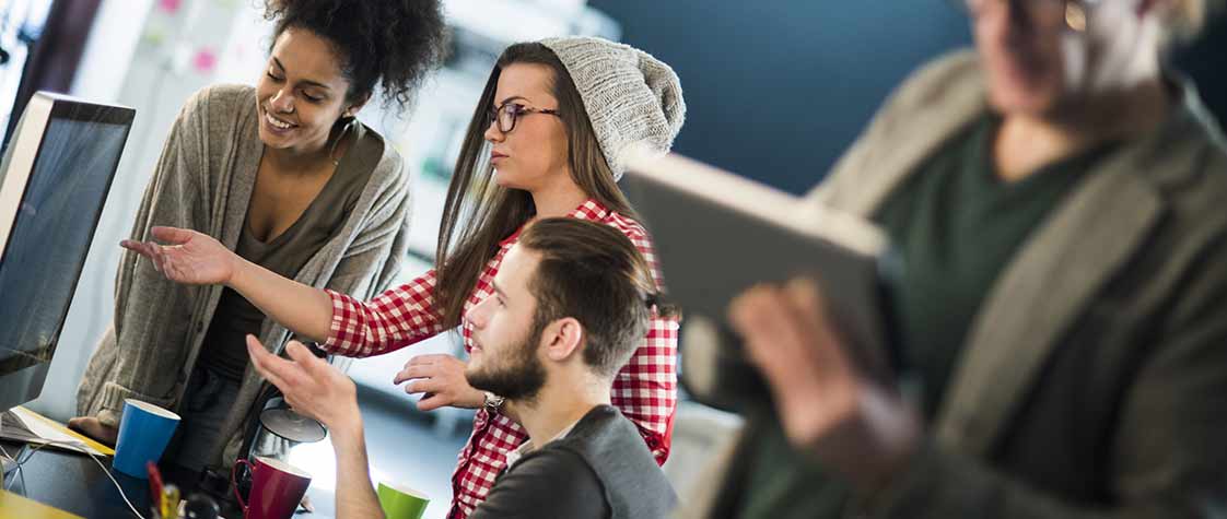 Trois étudiants échangent devant un écran d’ordinateur