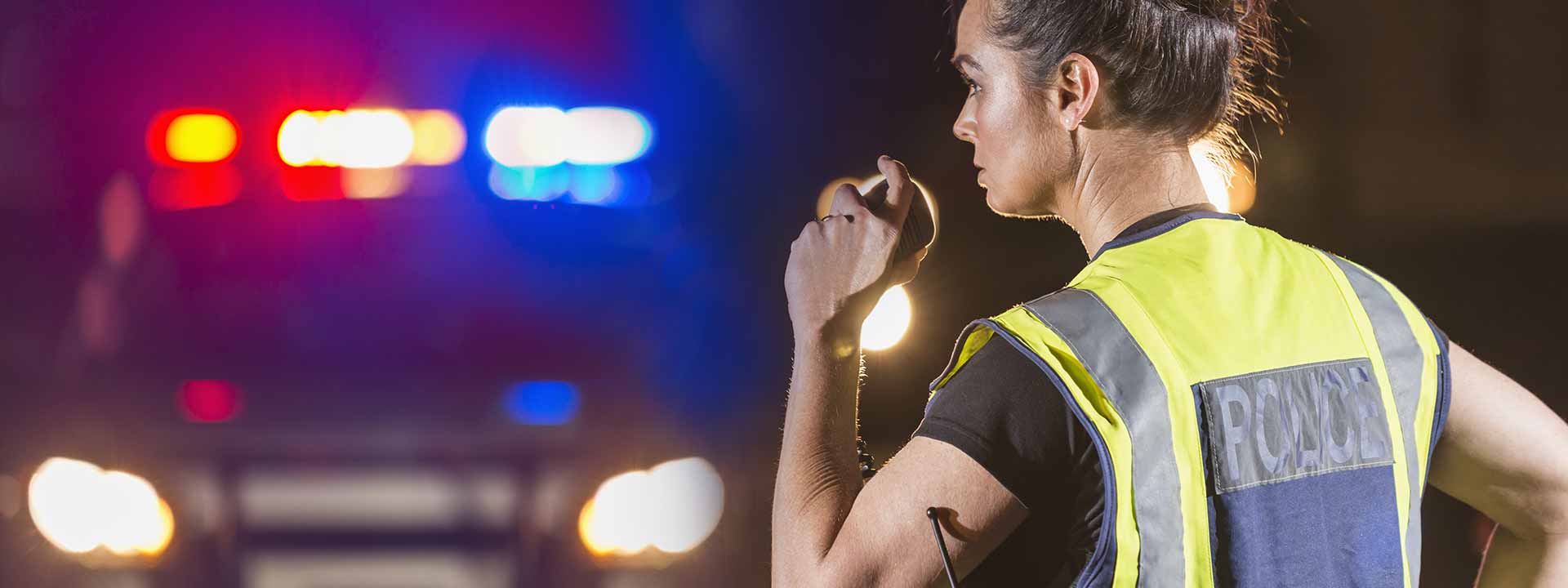 Une policière communique avec des collègues à l'aide d'une radio lors d'un contrôle routier.