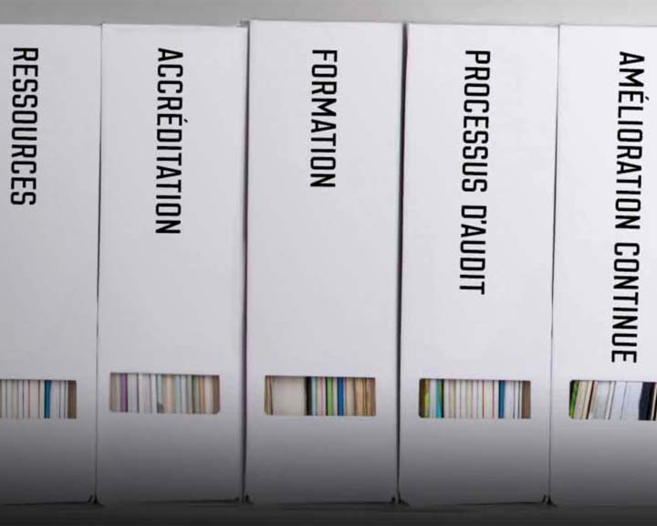 Manuels sur une étagère avec les mots, amélioration continue, processus d’audit, formation, accréditation, ressources