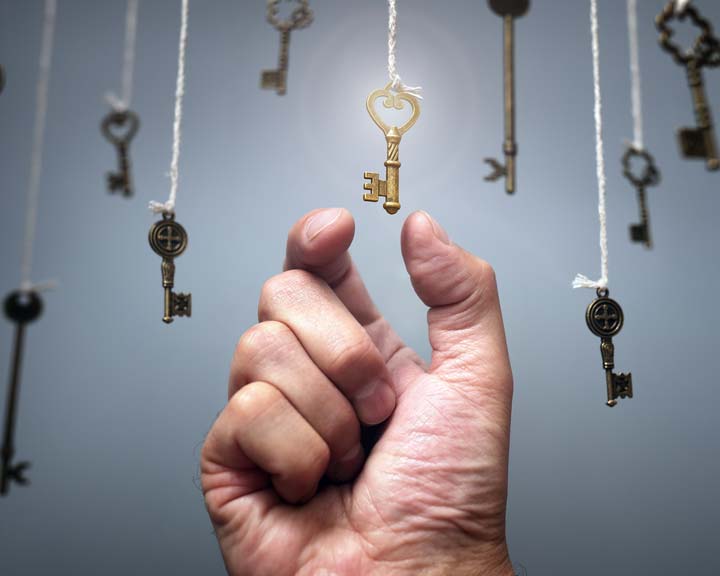La main d'un individu s'apprête à prendre une clé suspendue à une corde.
