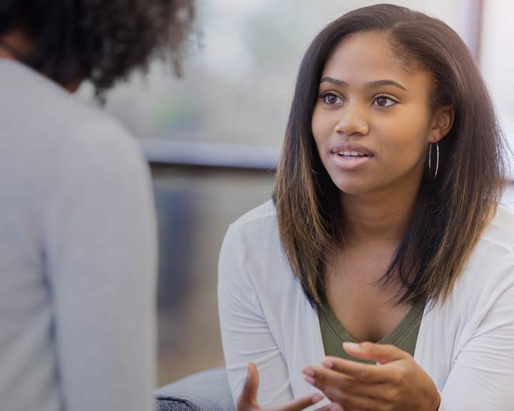 Étudiante souriante discutant avec une intervenante dans un espace d’accueil lumineux du collège.