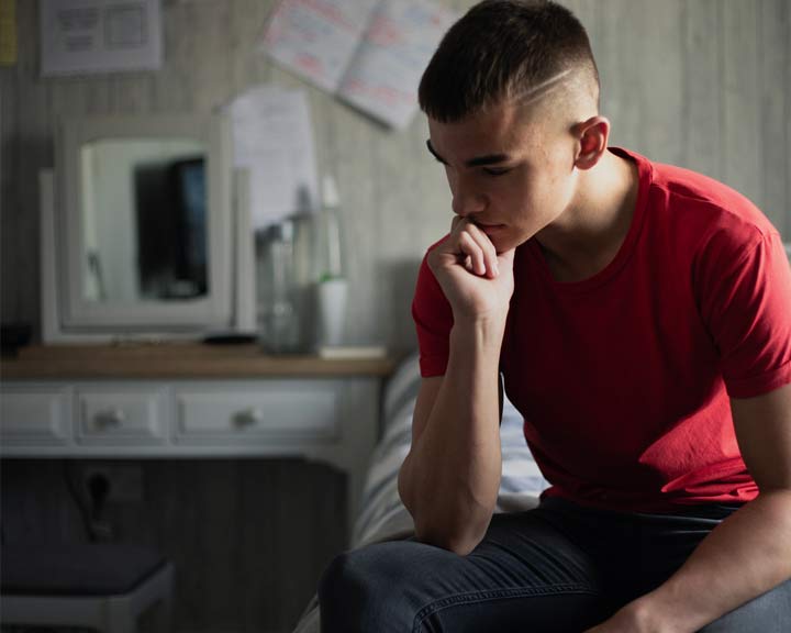 Étudiante assise seule, l’air préoccupé, illustrant un enjeu de santé mentale en milieu collégial.