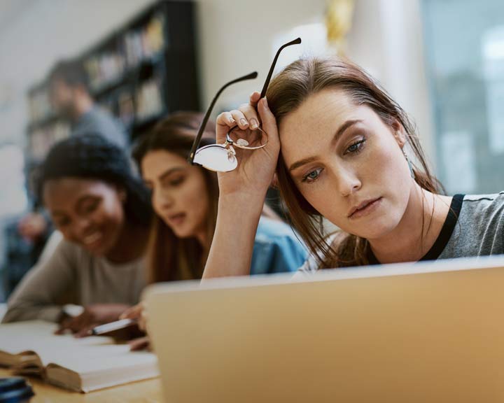 Étudiante travaillant sur un ordinateur portable dans un environnement académique.