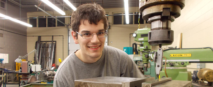 Un apprenti machiniste du programme d'apprentissage MACHINISTE usine une pièce.