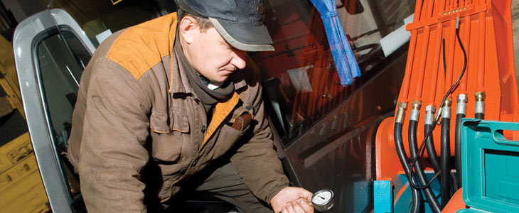 Mécanicien faisant des ajustements sur une machinerie hydraulique.