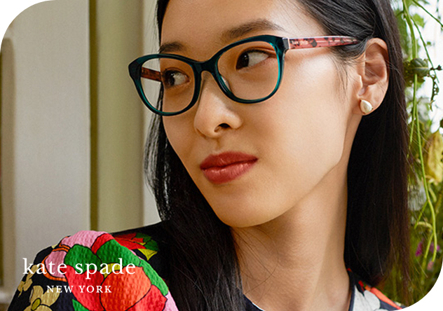 Une femme aux cheveux noirs porte des lunettes sur un selfie. La photo met en scène Kate Spade New York, suggérant un accessoire tendance.