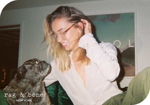 Une femme tient un chien dans ses bras, portant des lunettes de la marque Rag & Bone.