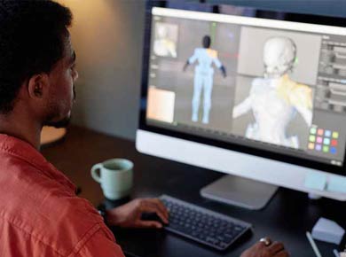 Individu assis au bureau tout en gérant un projet de modélisation 3D sur un écran d'ordinateur.
