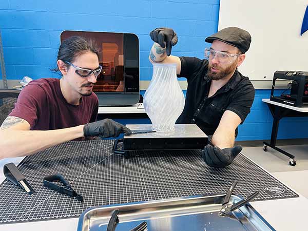 Deux hommes en atelier retirent le support d'un vase 3D translucid