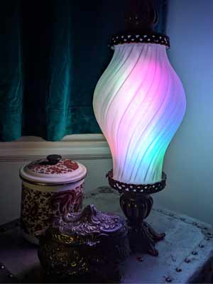Lampe décorative avec abat-jour translucide imprimé en 3D, illuminée par des lumières multicolores.
