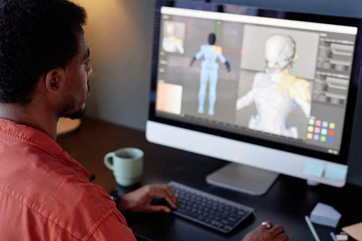 Individu assis au bureau tout en gérant un projet de modélisation 3D sur un écran d'ordinateur.