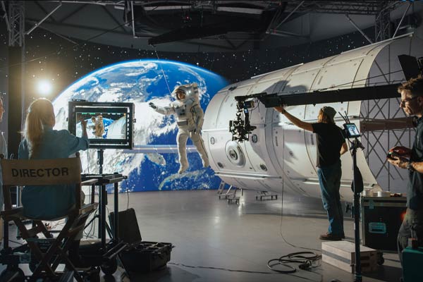 Une réalisatrice de renom dirige une équipe filmant un astronaute sur un plateau futuriste avec des effets visuels spatiaux avancés.