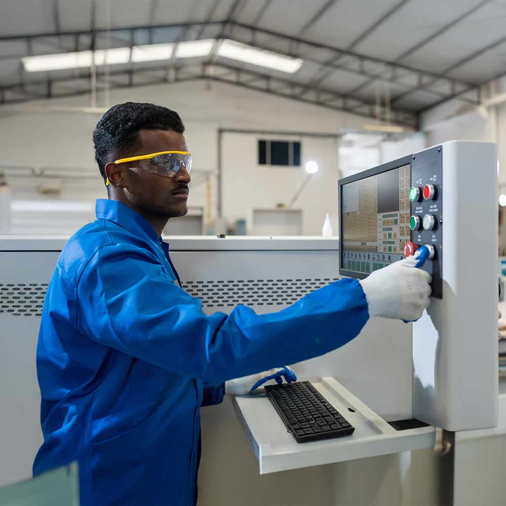 Male worker working with desk top computer for control CNC machine at workshop.