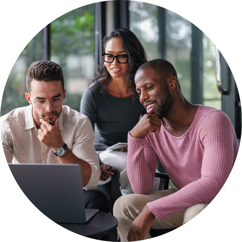 Une équipe diversifiée de trois professionnels, deux hommes et une femme, collaborant sur un ordinateur portable dans un bureau moderne et lumineux, baigné de lumière naturelle grâce à de grandes fenêtres.