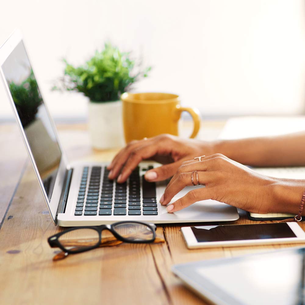 Femme d’affaires assise seule à la maison, tapant sur son ordinateur portable.