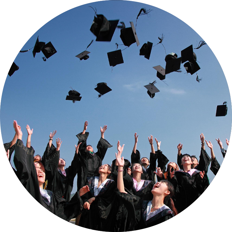 Cérémonie de remise des diplômes en plein air, avec des étudiants en toges noires lançant leurs mortiers en l’air sous un ciel bleu, exprimant joie et célébration.