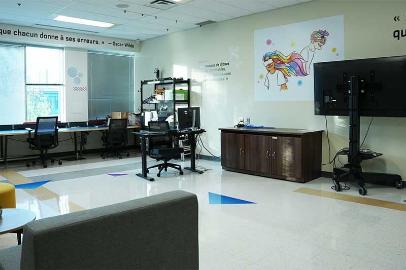 Bureau moderne, un environnement créatif, avec des postes de travail, un grand écran et une décoration artistique. La pièce est meublée de bureaux, de chaises et d'autres meubles et équipements de bureau.