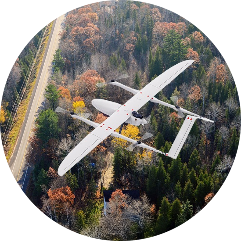 Vue aérienne d’un drone eVTOL blanc en vol au-dessus d’une forêt colorée en automne, montrant à la fois l’appareil et le paysage environnant.