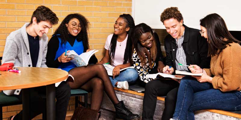 Un groupe de jeunes étudiants est assis ensemble et étudie. Ils semblent participer à un projet de groupe ou à un apprentissage collaboratif.
